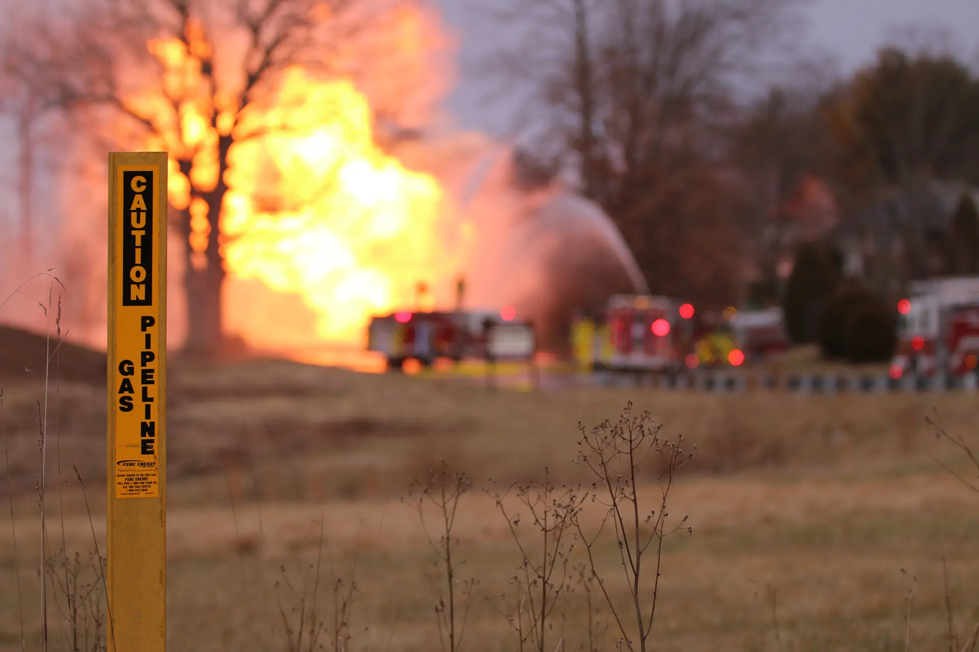 a caution pipeline sign in front of a fire