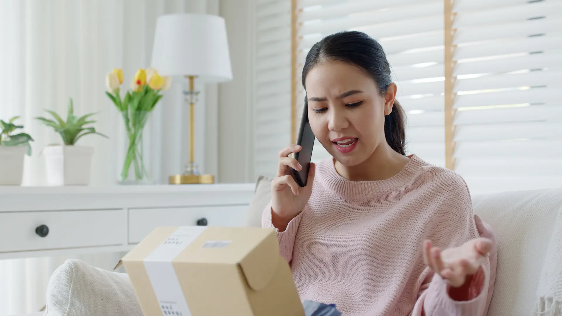 woman angrily on the phone holding a package