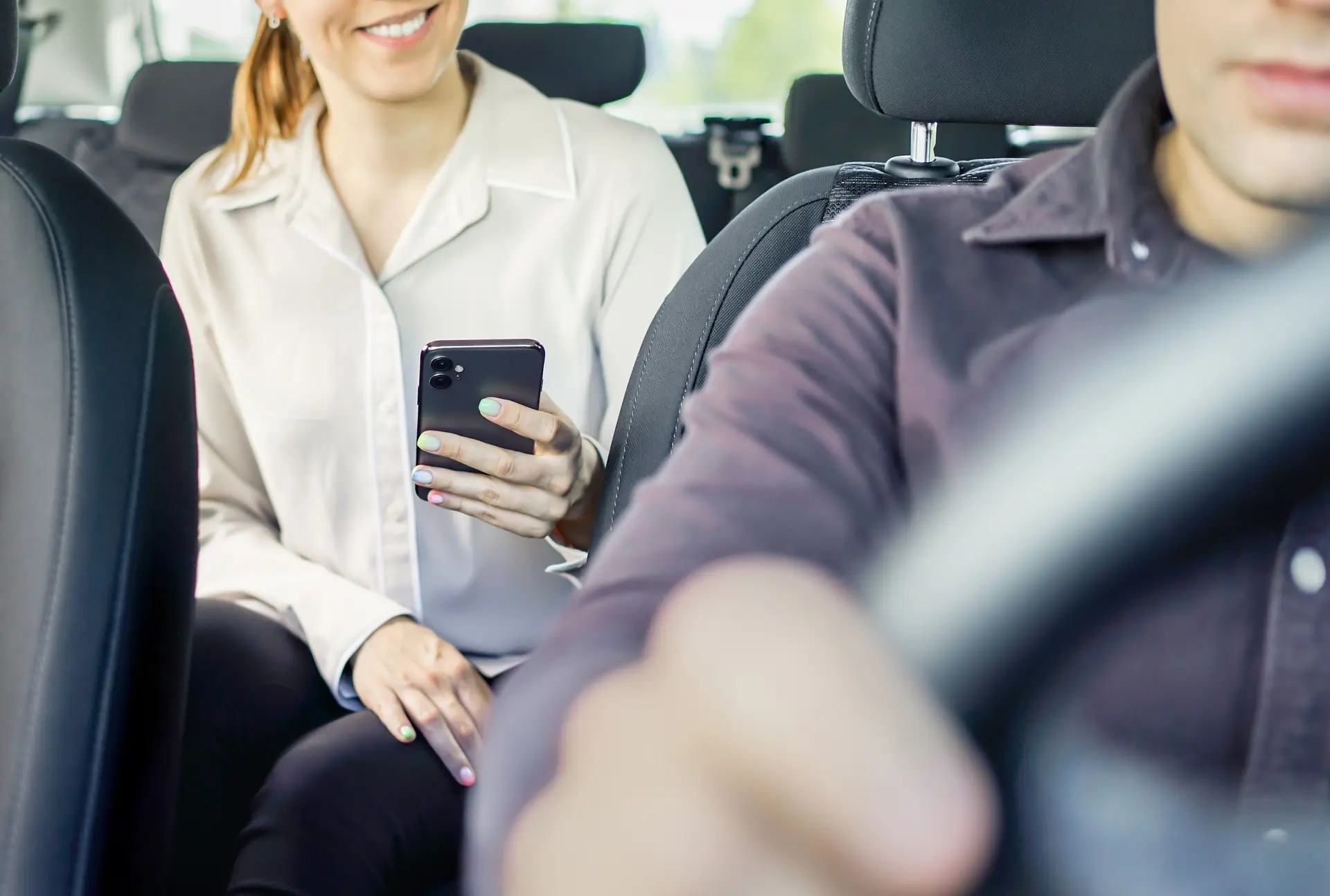 person in the backseat of car holding their phone